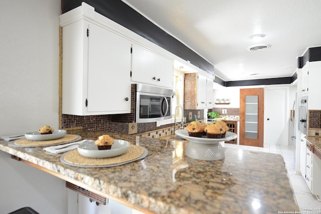 kitchen with white cabinetry and dark stone counters