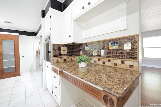 kitchen with tasteful backsplash, white cabinetry, and stone countertops