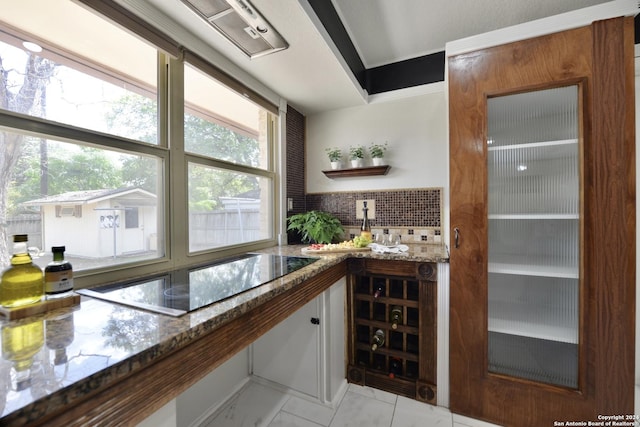 bar with black electric cooktop, decorative backsplash, and dark stone countertops