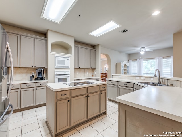 kitchen featuring white appliances, backsplash, sink, ceiling fan, and light tile patterned flooring