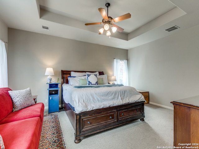 carpeted bedroom featuring a tray ceiling and ceiling fan