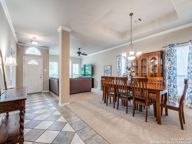 dining area featuring a raised ceiling, ornamental molding, ceiling fan with notable chandelier, and light tile patterned flooring