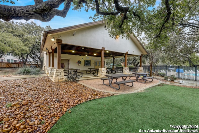 rear view of house featuring a patio area, fence, a lawn, and stucco siding