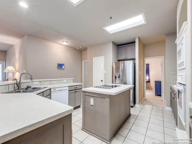 kitchen featuring gray cabinets, white appliances, light tile patterned floors, a center island, and sink