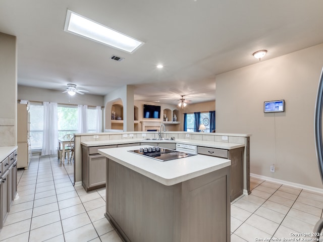 kitchen with kitchen peninsula, a kitchen island, light tile patterned floors, and ceiling fan