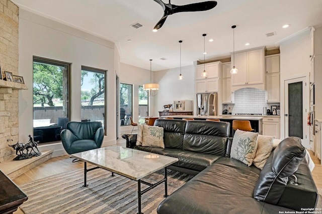 living room with ornamental molding, light hardwood / wood-style flooring, and ceiling fan