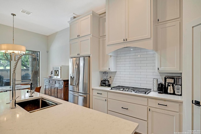 kitchen featuring decorative light fixtures, white cabinets, decorative backsplash, sink, and appliances with stainless steel finishes