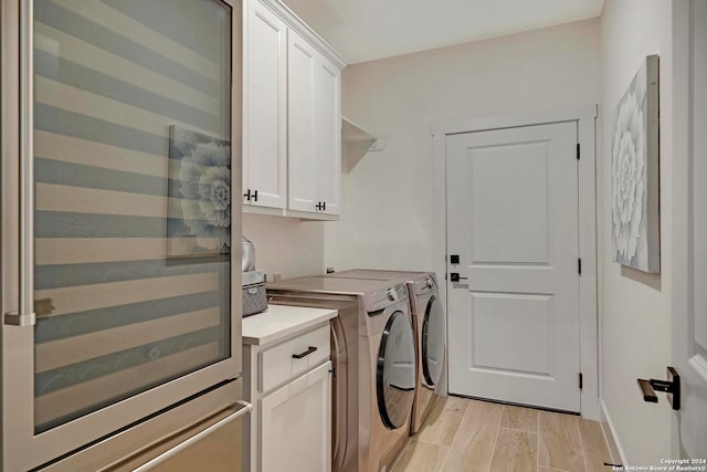 laundry room featuring independent washer and dryer, cabinets, and light hardwood / wood-style floors