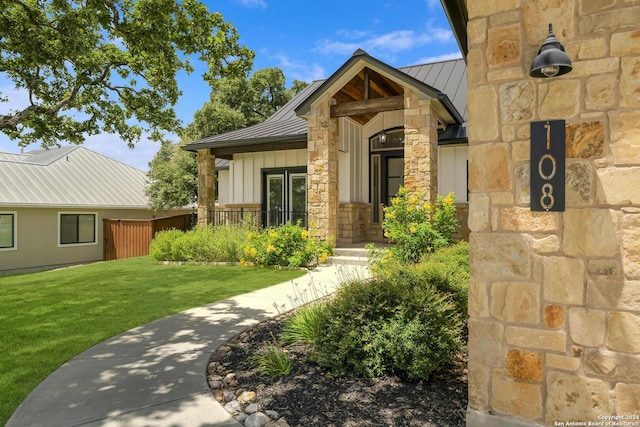 property entrance with metal roof, stone siding, board and batten siding, and a standing seam roof