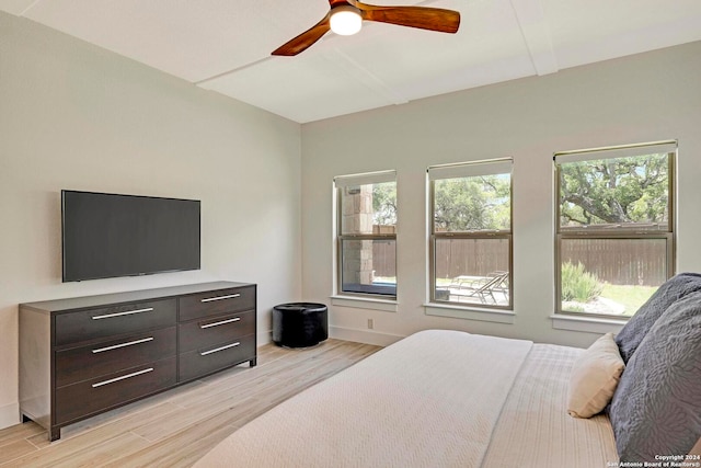 bedroom with ceiling fan, multiple windows, and light hardwood / wood-style flooring