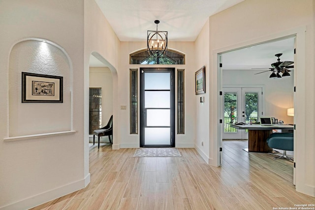 foyer with ceiling fan with notable chandelier and light wood-type flooring