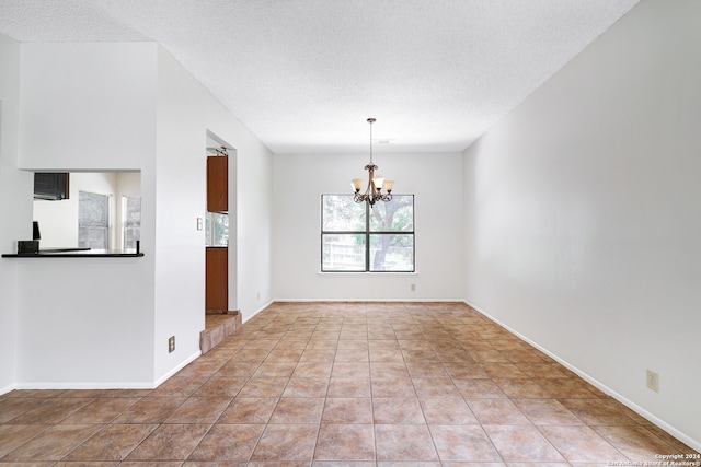 unfurnished dining area with a textured ceiling, light tile patterned floors, and a chandelier