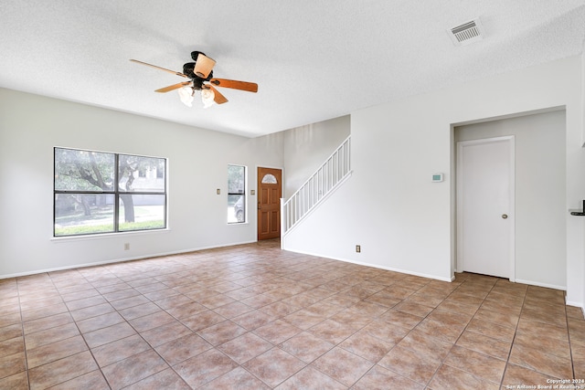 empty room featuring light tile patterned flooring, a textured ceiling, and ceiling fan