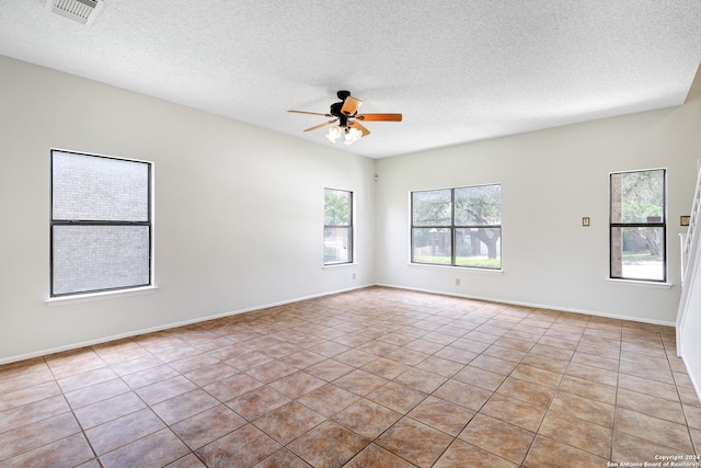 tiled spare room featuring plenty of natural light, a textured ceiling, and ceiling fan