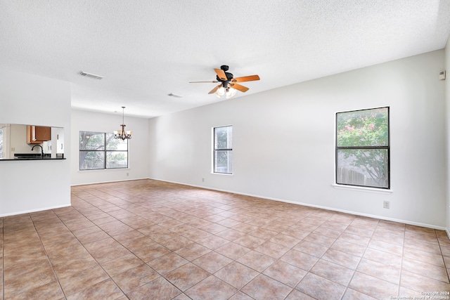 unfurnished living room with a textured ceiling, ceiling fan with notable chandelier, and light tile patterned floors