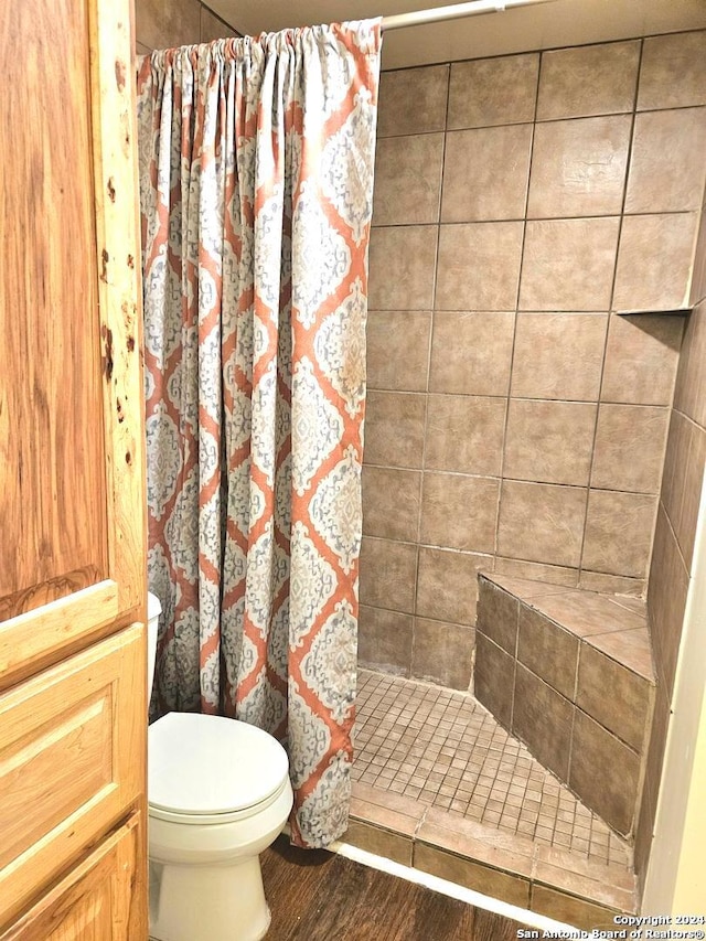 bathroom with wood-type flooring, toilet, and curtained shower