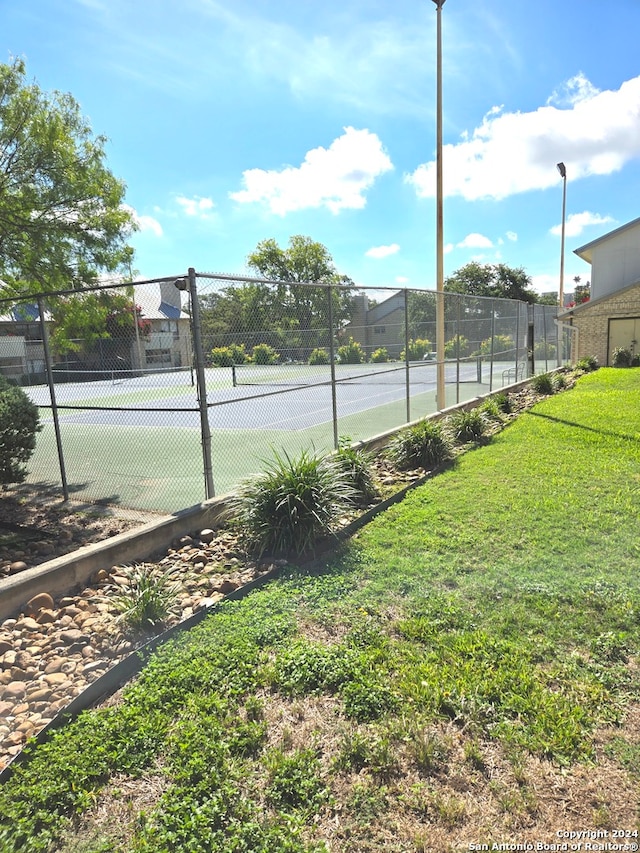 view of tennis court featuring a lawn