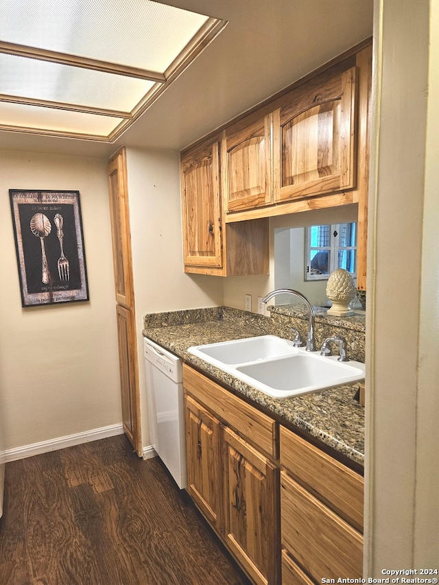 kitchen featuring dark stone countertops, sink, dark hardwood / wood-style flooring, and white dishwasher