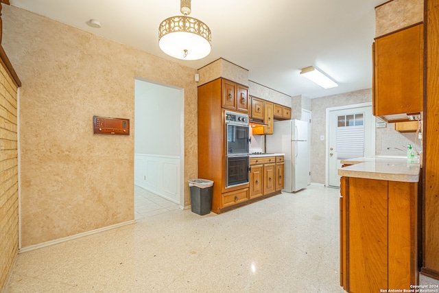 kitchen featuring sink, white fridge, and black double oven