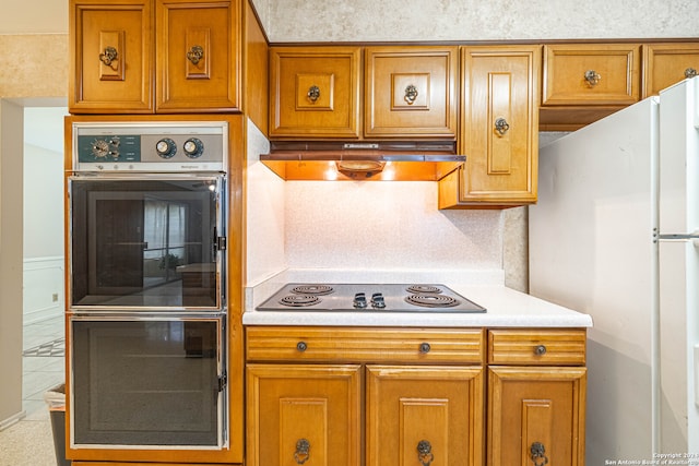 kitchen featuring gas stovetop, white fridge, and stainless steel double oven