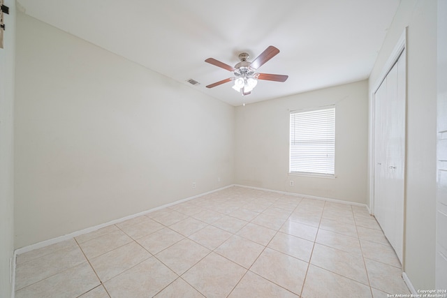 unfurnished bedroom with a closet, light tile patterned floors, and ceiling fan