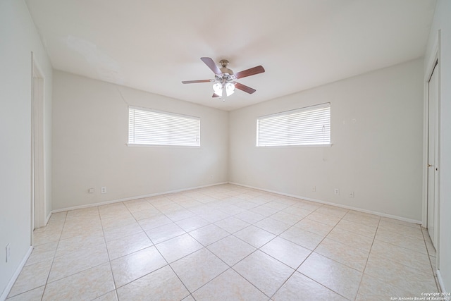 empty room featuring light tile patterned floors, a wealth of natural light, and ceiling fan