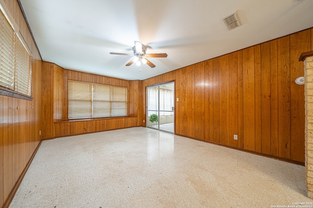 unfurnished room featuring wooden walls and ceiling fan