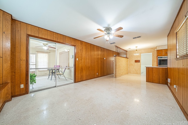 unfurnished living room with wood walls and ceiling fan