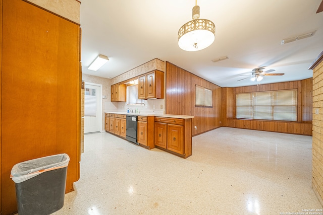 kitchen with wooden walls, sink, hanging light fixtures, dishwasher, and ceiling fan