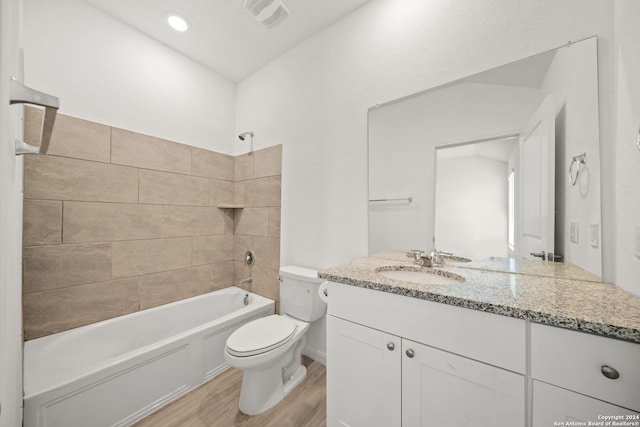 full bathroom with vanity, toilet, tiled shower / bath, and hardwood / wood-style floors