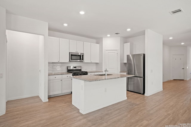 kitchen featuring white cabinetry, sink, appliances with stainless steel finishes, light hardwood / wood-style flooring, and backsplash