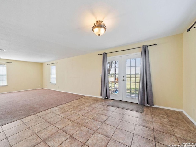 spare room with light tile patterned flooring, light colored carpet, visible vents, baseboards, and french doors