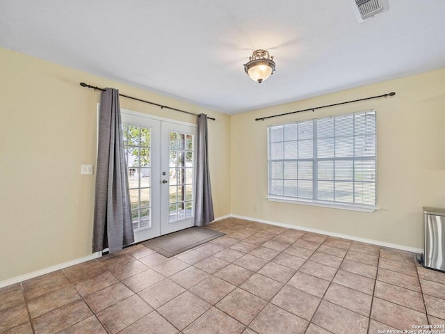 spare room featuring french doors, tile patterned flooring, visible vents, and baseboards
