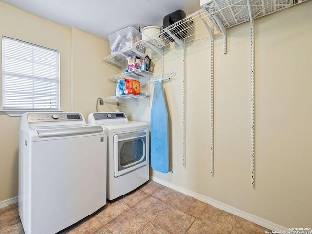 clothes washing area featuring laundry area, washing machine and dryer, light tile patterned floors, and baseboards