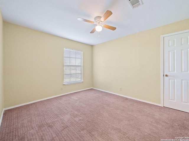 carpeted spare room featuring visible vents, ceiling fan, and baseboards