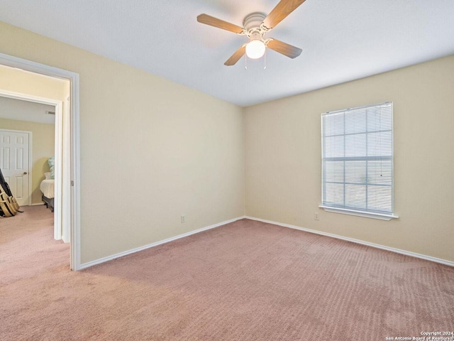 carpeted spare room with a ceiling fan and baseboards