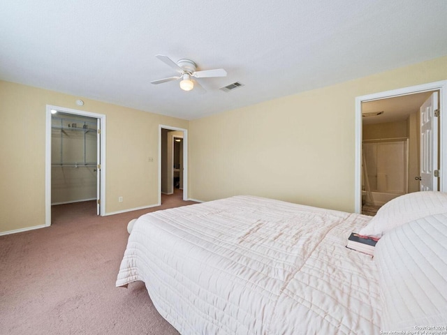 carpeted bedroom featuring a walk in closet, a closet, visible vents, a ceiling fan, and baseboards