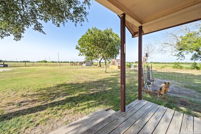 deck with a rural view, an outbuilding, and a lawn