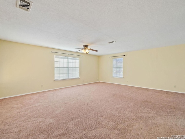 empty room featuring a textured ceiling, carpet floors, ceiling fan, and visible vents