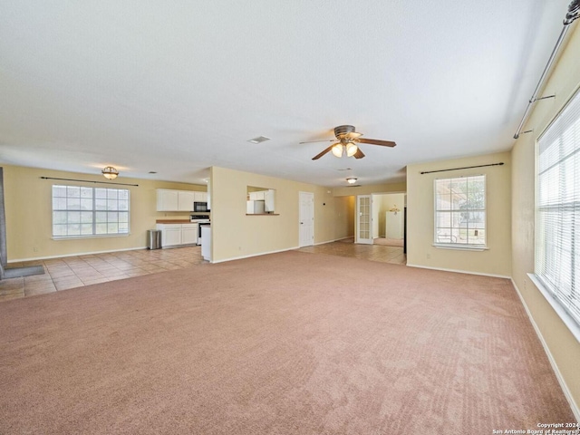 unfurnished living room with light tile patterned floors, baseboards, a ceiling fan, light colored carpet, and a textured ceiling