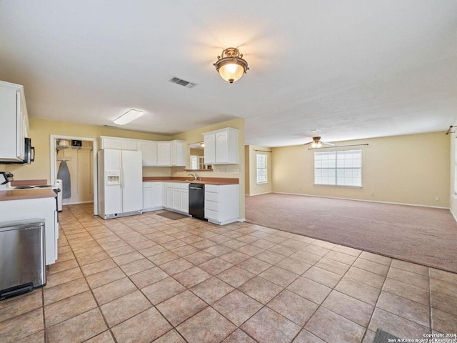 kitchen with light carpet, visible vents, white cabinets, open floor plan, and black appliances