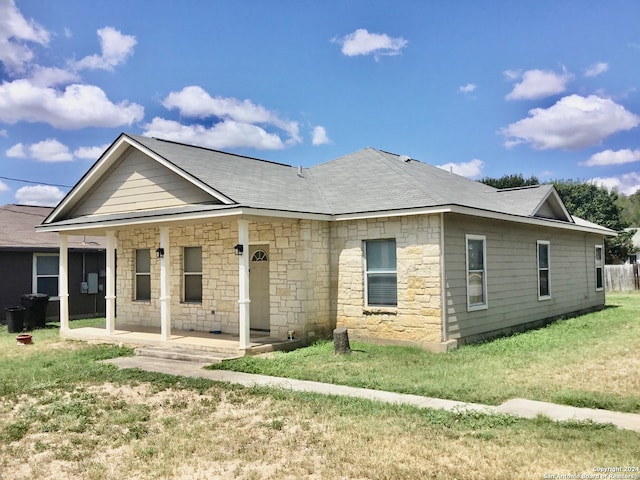 rear view of house featuring a lawn and covered porch