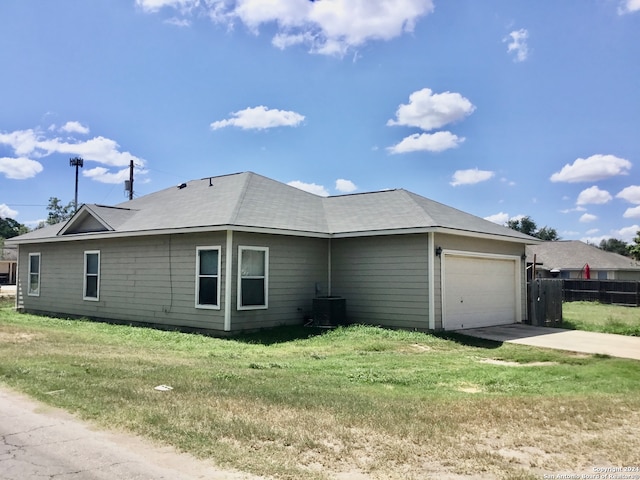 view of side of property featuring cooling unit, a garage, and a yard