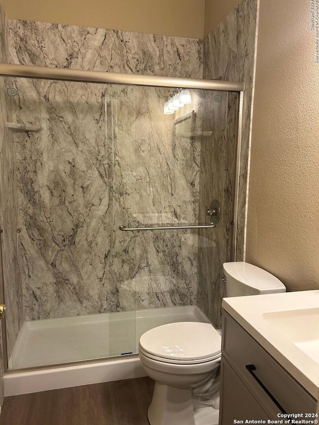 bathroom with hardwood / wood-style flooring, vanity, an enclosed shower, and toilet