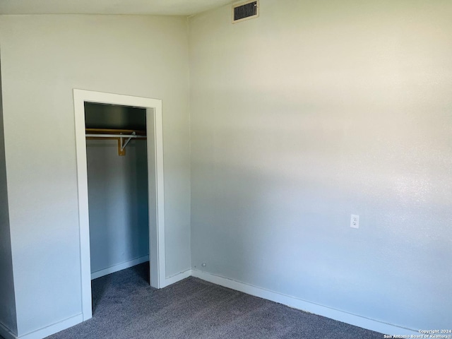 unfurnished bedroom featuring dark colored carpet and a closet