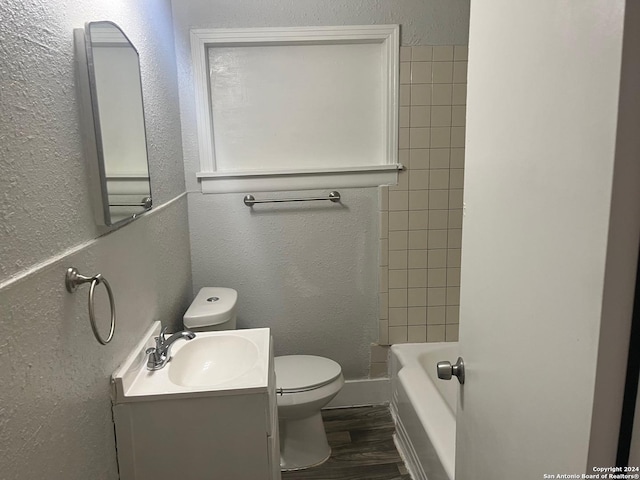 full bathroom featuring hardwood / wood-style flooring, tiled shower / bath, vanity, and toilet