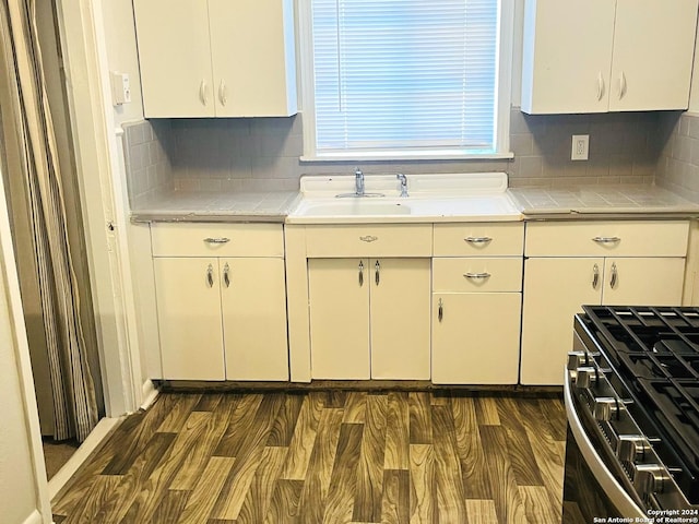 kitchen featuring dark hardwood / wood-style flooring, stainless steel gas stove, and white cabinets