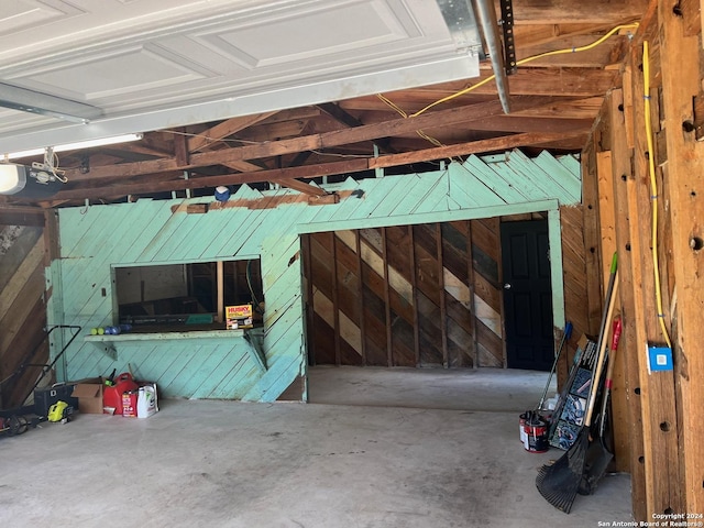 garage featuring a garage door opener and wooden walls