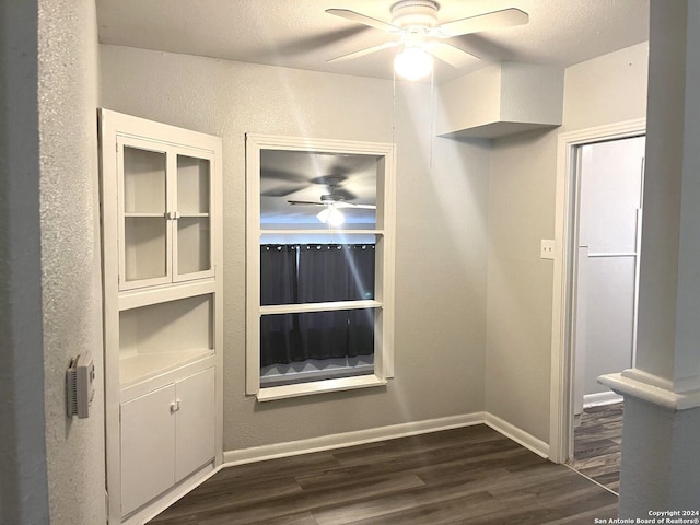 unfurnished dining area with dark wood-type flooring, ceiling fan, and a textured ceiling