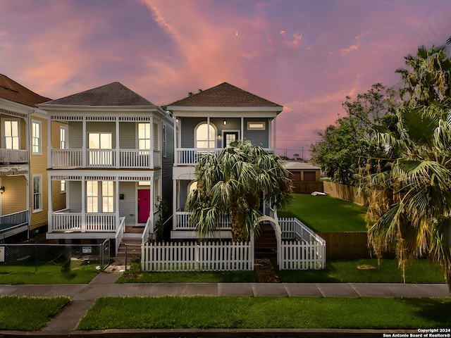 view of front of house featuring a yard, a balcony, and a porch